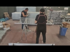 Gli operai stanno usando del filo per collegare la recinzione a maglie metalliche e il tubo del telaio